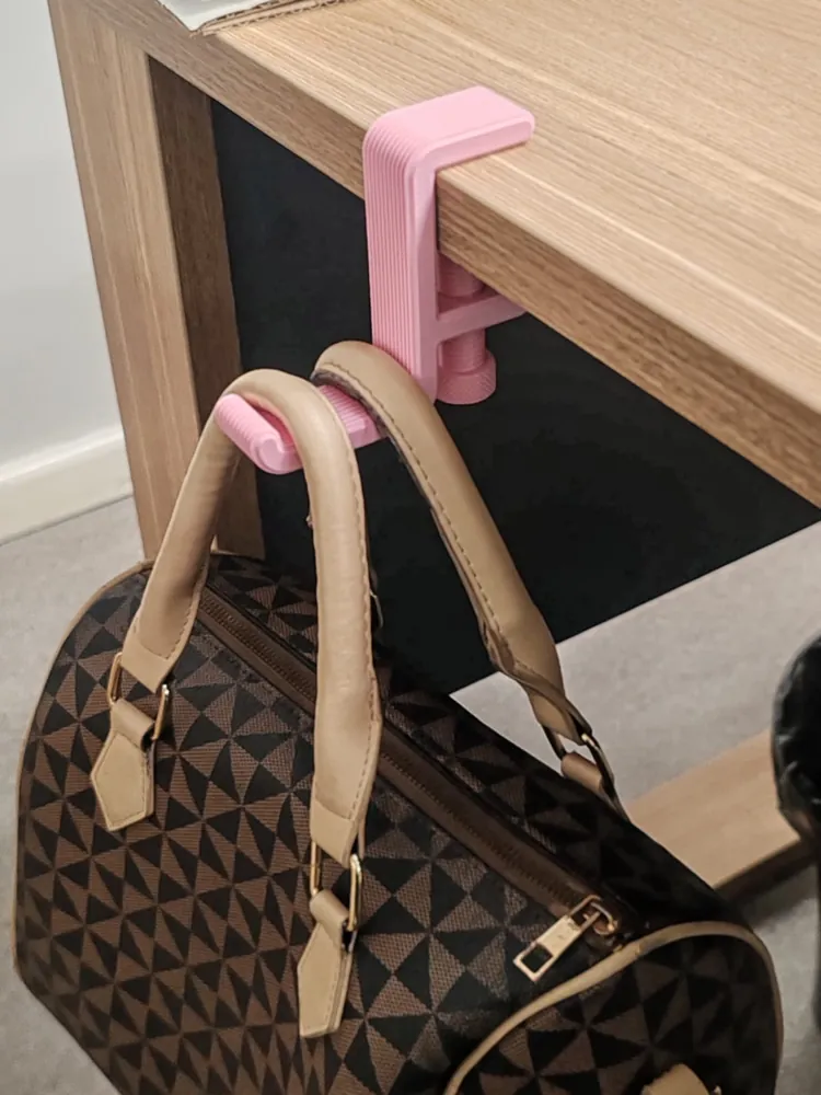 Pink clamp-on hook on a desk edge holding a handbag